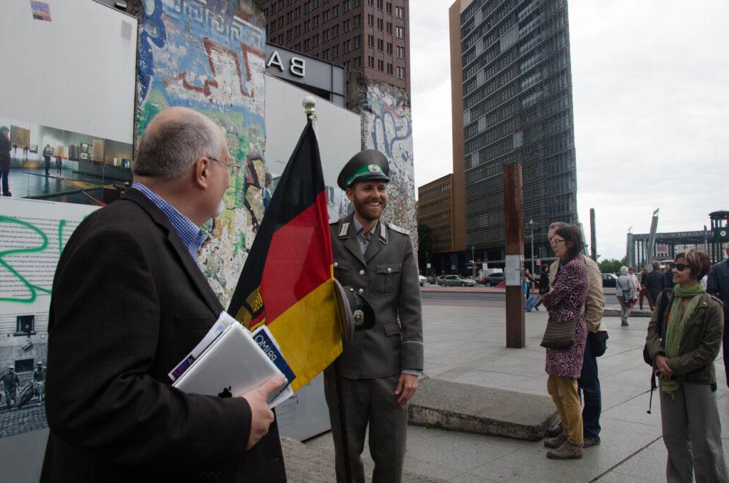 德国，两位教授站在一名士兵面前. 他举着一面德国国旗. 